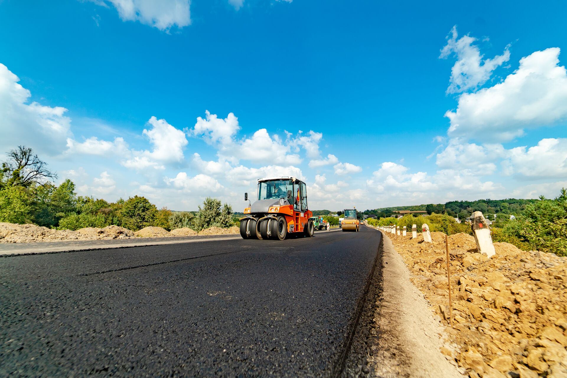 professional-equipment-lays-and-aligns-fresh-asphalt-on-the-highway-in-the-summer